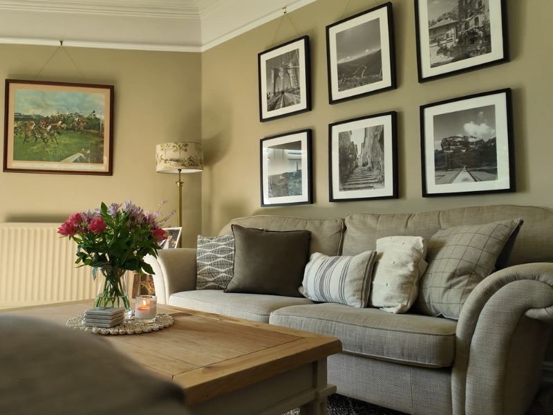 prikaz elegantnig dnevnog boravka sa slikama na zidu, ugaonom, stolčićem i cvećem