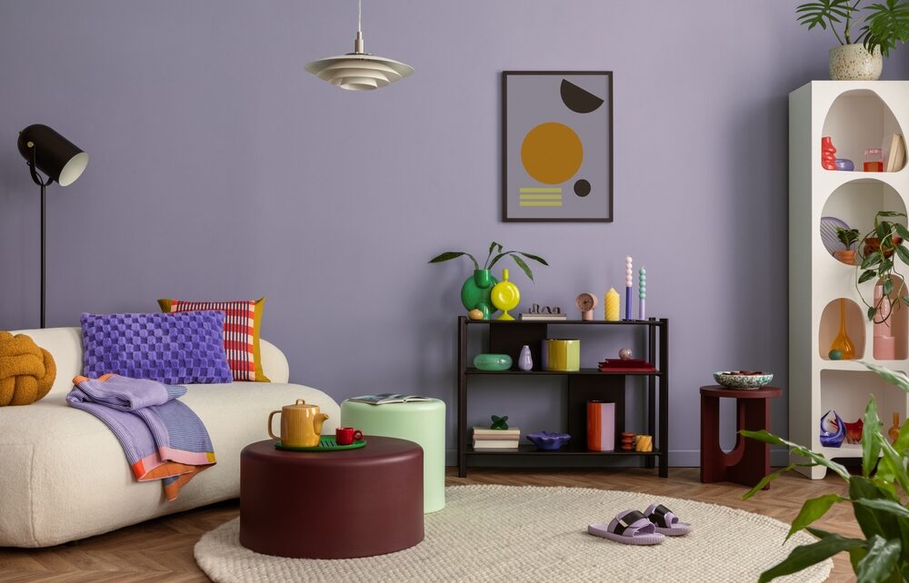 Dnevna soba sa pastelnim zidom i okruglim tepihom u svetloj nijansi koji se uklapa sa nameštajem