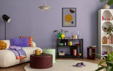 Dnevna soba sa pastelnim zidom i okruglim tepihom u svetloj nijansi koji se uklapa sa nameštajem