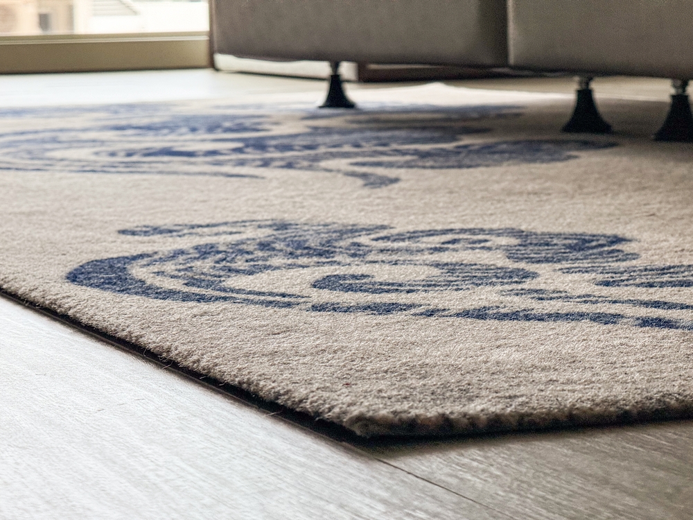 Tepih u neutralnim tonovima postavljen na pod koji se uklapa sa bojom enterijera