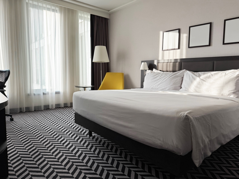 Spavaća soba sa neutralnim zidovima i dezeniranim tepihom koji daje eleganciju prostoru